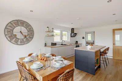 a kitchen with a table and a clock on the wall at Berryrigg Cottage in Dumfries
