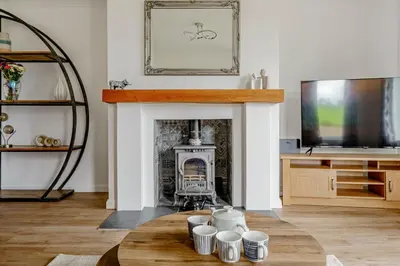 a living room with a fireplace and a table at Berryrigg Cottage in Dumfries