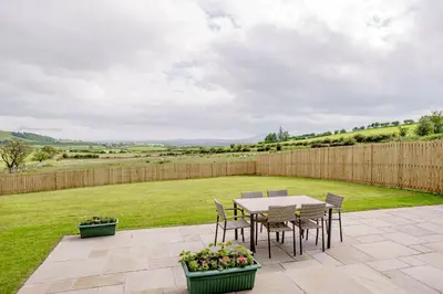 a patio with a table and chairs and a fence at Berryrigg Cottage in Dumfries