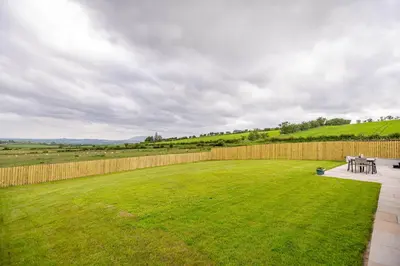 a backyard with a fence and a grassy yard at Berryrigg Cottage in Dumfries