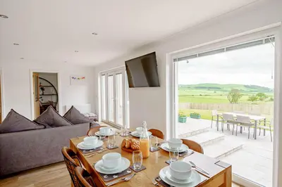 a living room with a table and a couch at Berryrigg Cottage in Dumfries