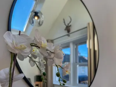 a vase with white flowers in front of a mirror at Anley Cottage with garden and private parking in Keswick in Keswick
