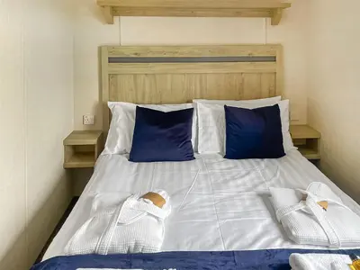 a bedroom with a bed with blue and white pillows at Seaview 61-Uk46904 in Mainsriddle