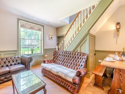 a living room with leather furniture and a table at The Coach House in Longtown