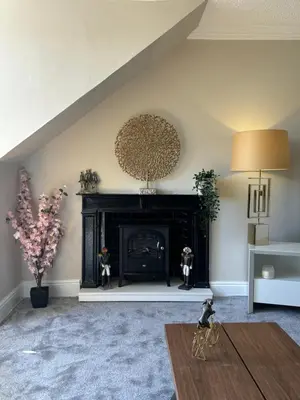 a living room with a fireplace and a table at Golfers Rest in Ayr