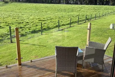 a deck with two chairs and a view of a field at Livingstones Lodge, Lake District in Plumbland