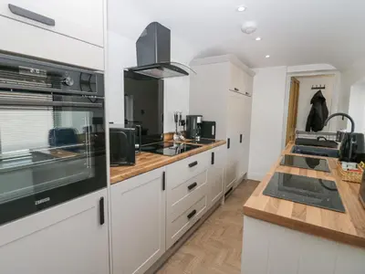 a kitchen with white cabinets and a black appliance at Victroneen Cottage in Whitehaven