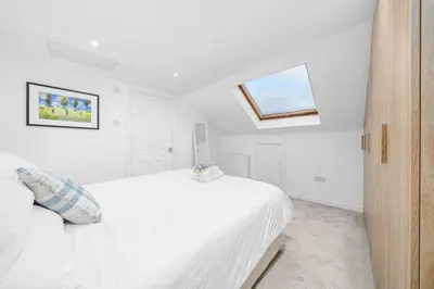 a white bedroom with a white bed and a window at Perfect location for beach and golfing in Troon