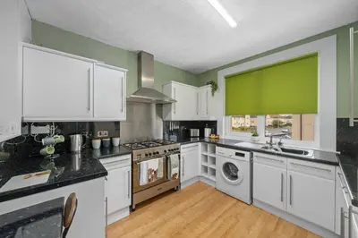 a kitchen with white cabinets and a green wall at Royal Troon Golf Let in Troon