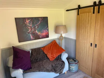 a living room with a couch and a picture of a deer at Millburn Mini Farm in Kilwinning