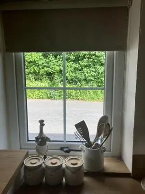 a window with a bunch of kitchen utensils on a counter at Annie's Cottage in Gosforth