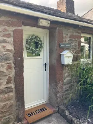 a white door on the side of a stone house at Annie's Cottage in Gosforth