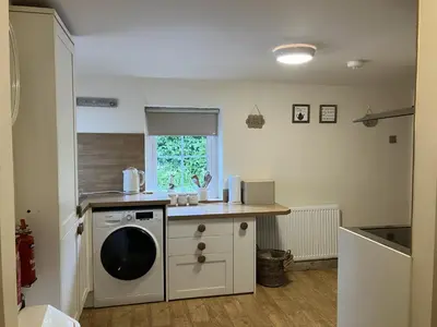 a kitchen with a washing machine and a sink at Annie's Cottage in Gosforth