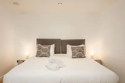 a bedroom with a large white bed with two lamps at Wellington Lodge in Ayr