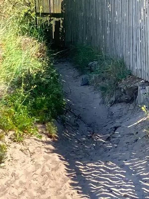 a shadow of a fence on the sand near a wall at Wee Beach Hut Maidens in Maidens