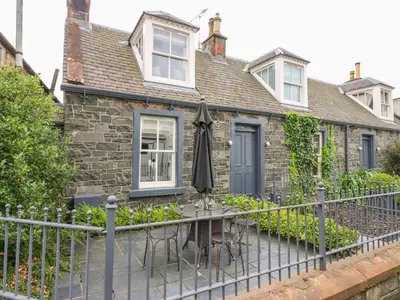 a house with a table with an umbrella in front of it at Wee Cottage in Moffat
