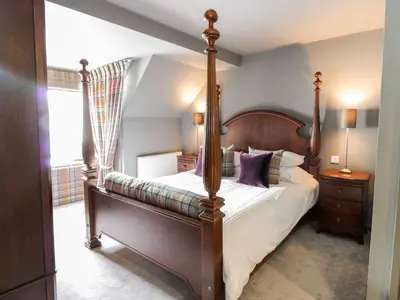 a bedroom with a four poster bed with purple pillows at Wee Cottage in Moffat