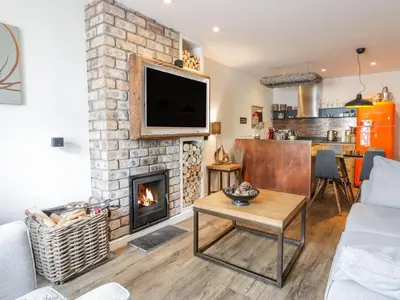 a living room with a fireplace and a tv at Wee Cottage in Moffat