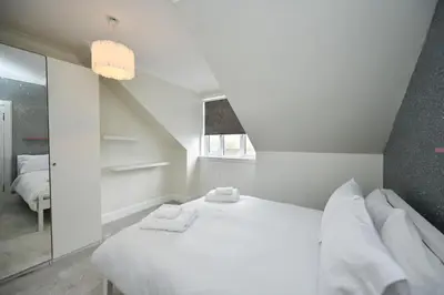 a white bedroom with a bed and a mirror at Arran View in Prestwick in Prestwick