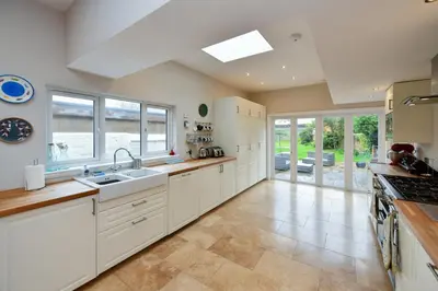 a large kitchen with white cabinets and a sink at Arran View in Prestwick in Prestwick
