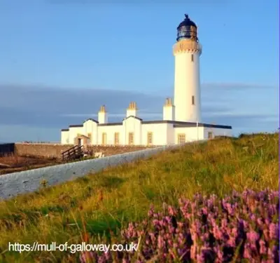 a lighthouse on top of a hill with flowers at The Galloway Steading - The Fox's Den with Hot Tub and Fire Pit in Glenluce