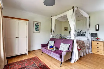 a bedroom with a purple couch and a canopy bed at Finest Retreats - Unerigg in Grasmere