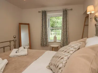 a bedroom with a bed and a window at Heather's Cottage in Carlisle
