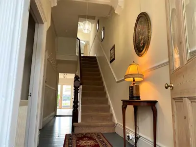a hallway with stairs and a lamp on a table at Tre in Douglas