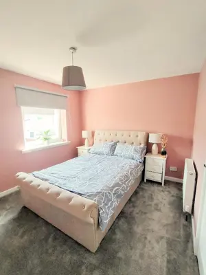 a bedroom with a large bed with pink walls at Troon Beach and Golf House in Barassie
