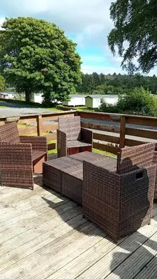 a group of wicker chairs and tables on a deck at Baytree Lodge at three lochs holiday park, NEW ASK ABOUT OUR PACKAGES birthday ,anniversary,family,pamper packages available in Balminnoch