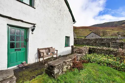 a green door and a bench outside of a building at Finest Retreats - Town Head Cottage in Grasmere in Grasmere