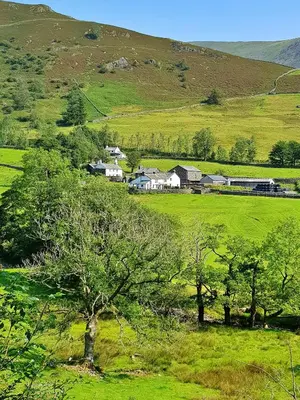 a green field with houses and trees in front of a hill at Finest Retreats - Town Head Cottage in Grasmere in Grasmere