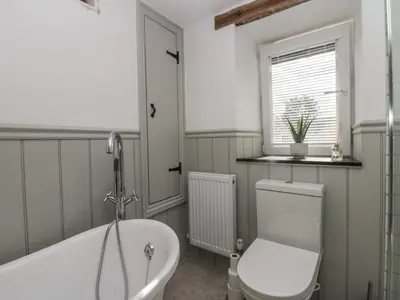 a bathroom with a tub and a toilet and a sink at Style Cottage in Keswick