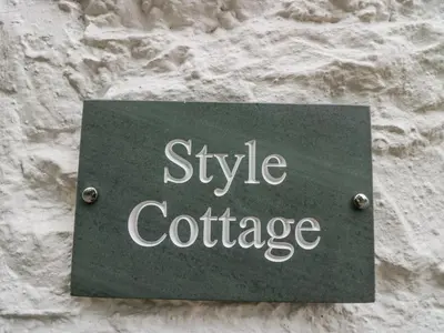 a sign on a stone wall with the words style patronage at Style Cottage in Keswick
