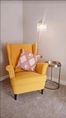 a yellow chair with two pillows sitting next to a lamp at Troon Golf and Beach House in Troon