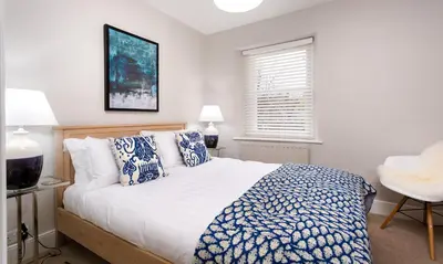 a bedroom with a bed with blue and white pillows at Pippin Cottage in Keswick