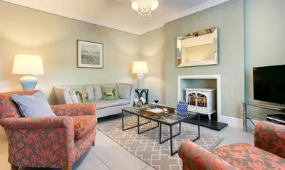 a living room with couches and a tv and a fireplace at Pippin Cottage in Keswick