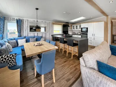 a kitchen and living room with a table and blue chairs at Uk47534 - Sea View 82 in Mainsriddle