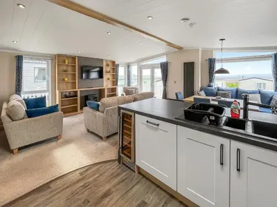 a kitchen with a sink and a living room at Uk47534 - Sea View 82 in Mainsriddle
