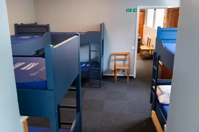 a room with bunk beds and a table and a chair at Weirside, Chapel Stile in Ambleside