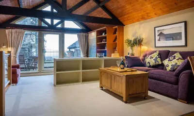 a living room with a purple couch and a table at Underscar - Beckstones in Keswick