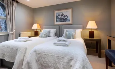 a bedroom with two beds with white sheets and lamps at Underscar - Beckstones in Keswick