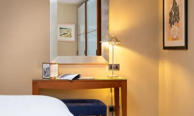a bedroom with a bed and a desk with a mirror at Underscar - Beckstones in Keswick
