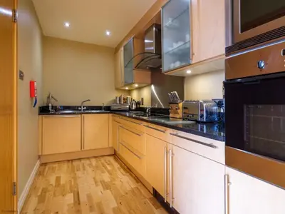 a kitchen with wooden cabinets and black appliances at Underscar - Grange in Keswick