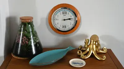 a table with a clock and a fish and a bottle at Little Egret in Carsethorn