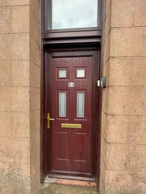a red door on a building with a window at DG1 1ST Floor Flat in Dumfries