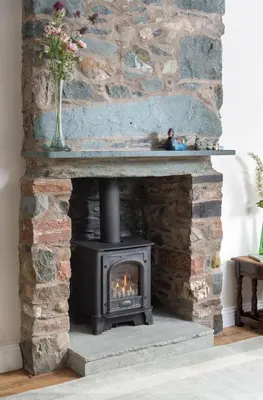 a fireplace with a stove in a living room at Lydia's River Cottage in Keswick