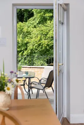 an open door to a patio with a table and chairs at Lydia's River Cottage in Keswick