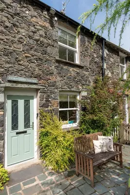 a stone house with a green door and a bench at Lydia's River Cottage in Keswick