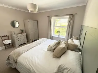 a bedroom with a large white bed and a window at Kionslieu Farm Cottages in Foxdale